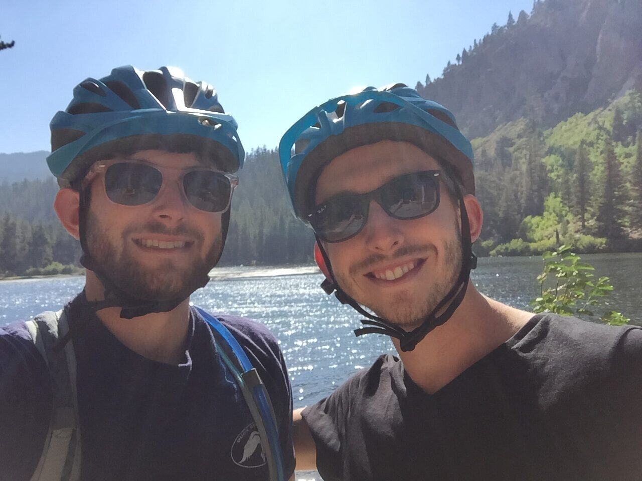 Two cyclists in helmets by mountain lake