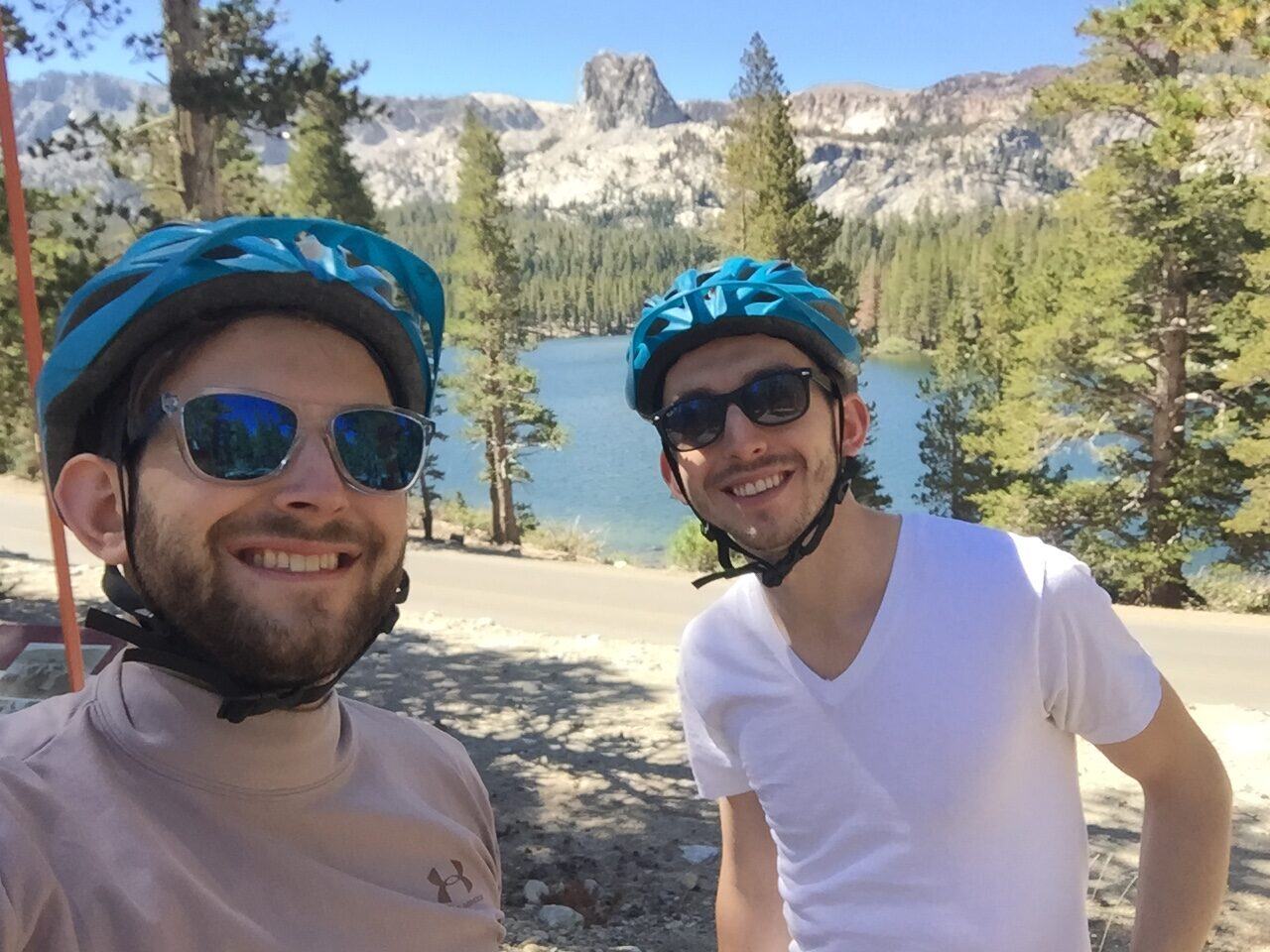 Two helmeted cyclists at mountain lake