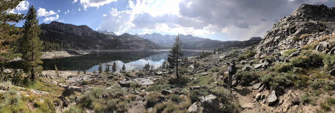 Panorama of alpine lake below rocky ridges