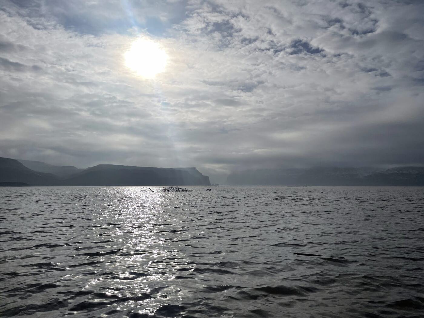 Sun breaking through clouds over open water