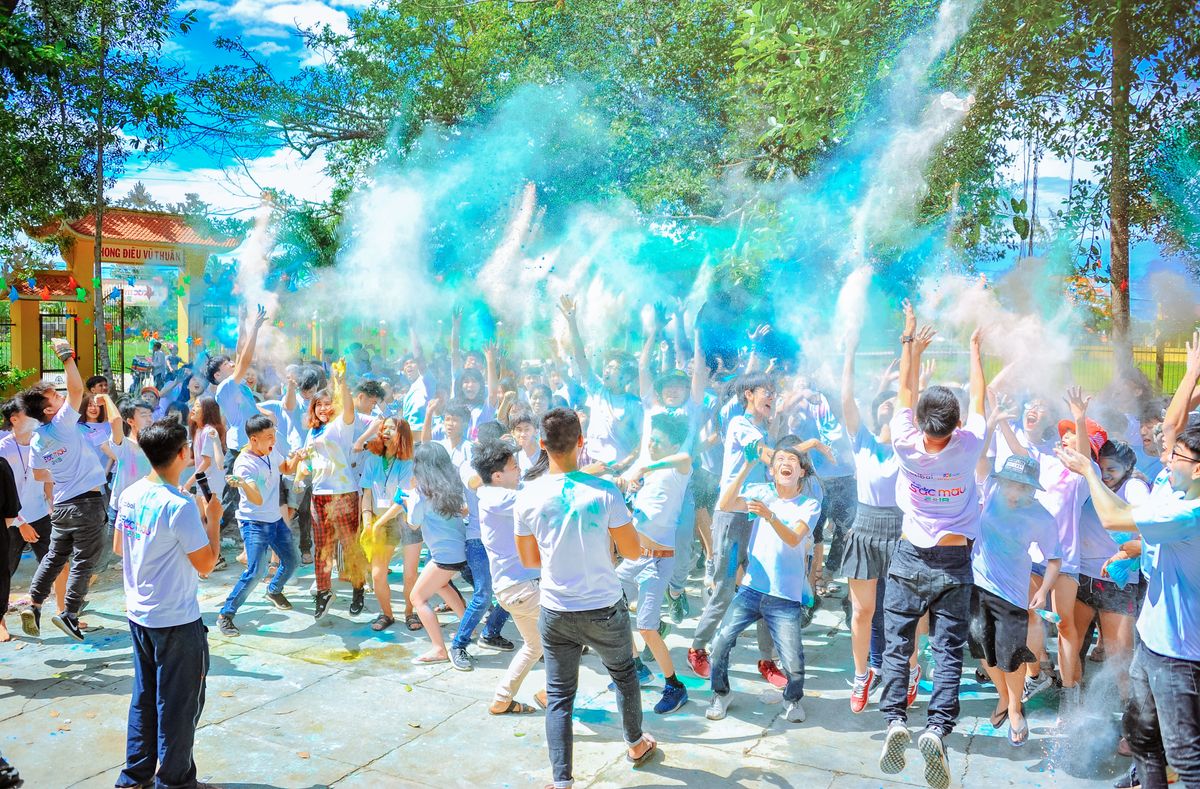 Crowd throwing blue powder at outdoor color run festival