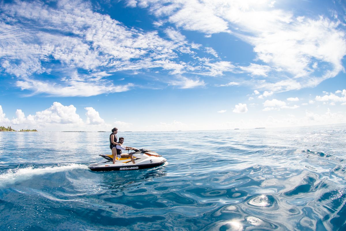 Rider on jet ski crossing turquoise ocean under big sky