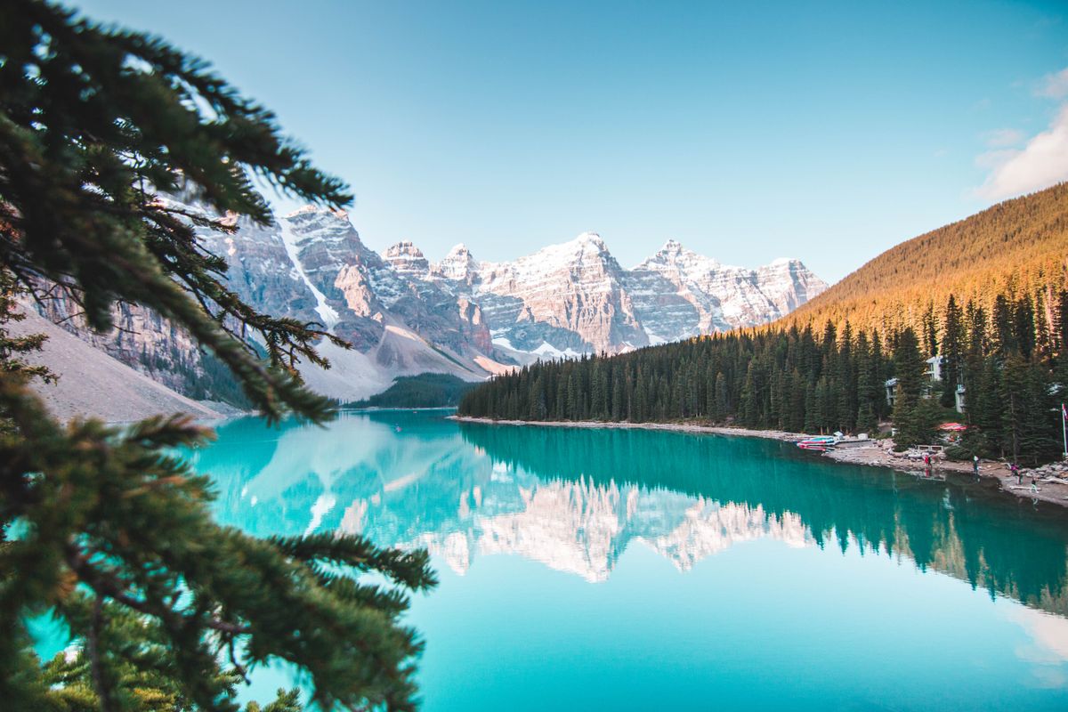 Turquoise glacial lake framed by pines and snowy mountains